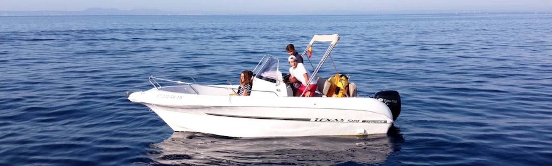 La moderna lancha TEXAS 580 con un grupo de participantes divirtiéndose mientras navegan por las aguas turquesas de la bahía de roses durante un alquiler de barco en la Costa Brava para hasta 6 personas con licencia con Maxi Boats.