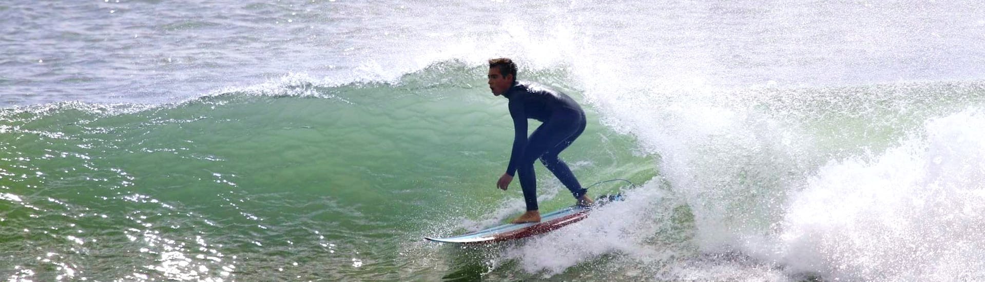 Ein Mann surft während seiner ersten Surfstunde in der Nähe von Lissabon in Costa da Caparica mit der GetWet Surf School.