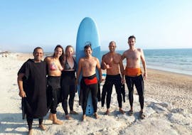 Un gruppo di persone sorridono dopo la loro lezione di surf vicino a Lisbona a Costa da Caparica con GetWet Surf School.