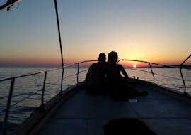 Bild eines Paares auf einem Boot von Leucos Escursioni Leuca bei Sonnenuntergang während der Bootstour von Santa Maria di Leuca zu den Meeresgrotten.