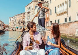 A couple on the gondola while they open a bottle of prosecco during the Private Gondola Ride in the Grand Canal with Prosecco with Agenzia Gondolieri Travel Venezia.
