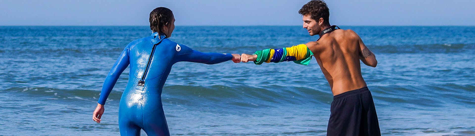 Two people fist bump during a private surf lesson in Praia do Tarquínio with Gota Dagua Surf School.