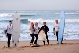 Eine Gruppe von Leuten mit ihren Surfbrettern während eines Surfkurses in Ericeira am Praia de Ribeira d'Ilhas mit der Ericeira Waves Surf School.