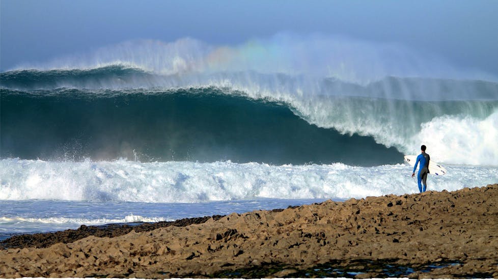 Una persona mirando las olas durante una lección privada de surf en Praia de Ribeira d'Ilhas con Ericeira Waves.