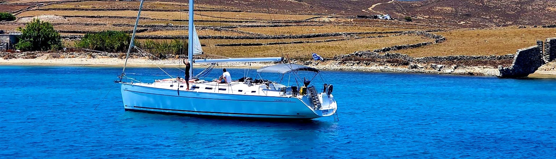 Een groep vrienden zeilend over de Egeïsche Zee op een elegante zeilboot tijdens een zeilboottocht naar het eiland Rhenia met lunch met Set Sail Mykonos.