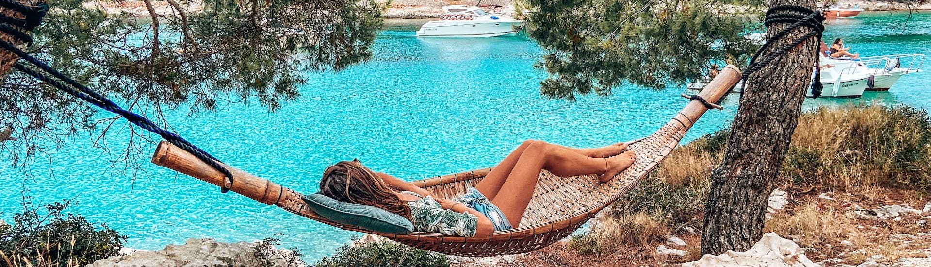 Eine Frau entspannt in einer Hängematte auf einer Insel während der Private Bootstour entlang der Küste Šibeniks mit Anima Natura Šibenik.