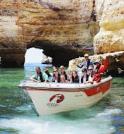 Mensen navigeren tijdens een boottocht van Armação de Pêra naar 10 grotten waaronder Benagil met Aurora Boat Trips.