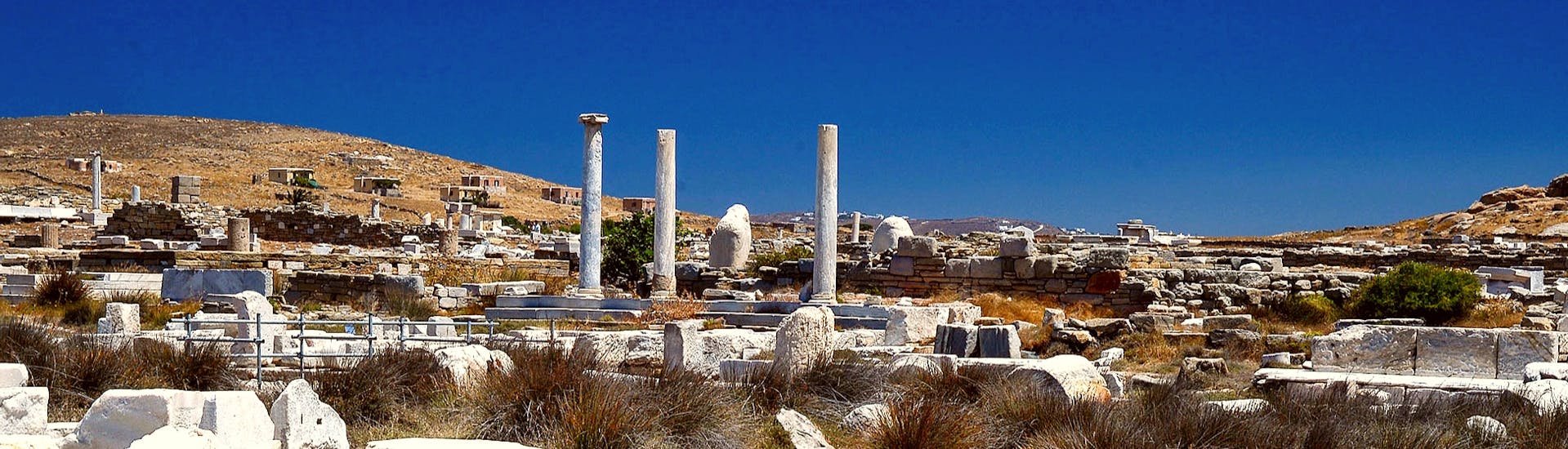 Die antike archäologische Stätte von Delos an einem sonnigen Tag, mit Teilnehmern, die während eines Segelboottour nach Rineia und Delos mit Schwimmen mit Set Sail Mykonos herumspazieren.