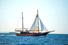 An elegant wooden boat standing on the turquoise waters of the Icarian Sea, with participants during a sailing boat trip to the islands of Kalymnos, Plati & Pserimos with Odyssey Boat.