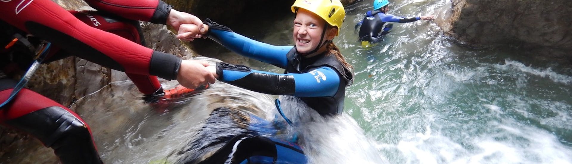 A girl sliding down a waterfall during the Private Kids canyoning in Windau with Outdoor Guide.Tirol.