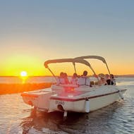 Ein Boot auf dem Meer vor dem wunderschönen Sonnenuntergang während der Bootstour bei Sonnenuntergang ab Faro entlang der Ria Formosa mit Lands Algarve.