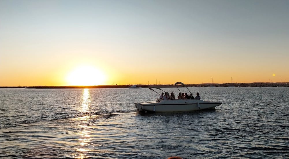 Un grupo de participantes disfrutando de una hermosa puesta de sol sobre la Ría Formosa durante un viaje en barco al atardecer desde Faro a lo largo del río con Lands.