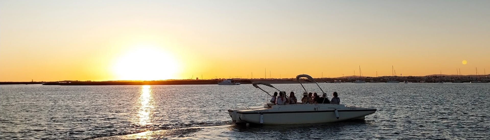 Een groep deelnemers geniet van een prachtige zonsondergang over de Ria Formosa tijdens een zonsondergangboottocht vanuit Faro langs de rivier met Lands Algarve.