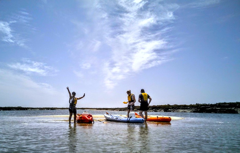 Un gruppo di partecipanti si gode una giornata in kayak, fermandosi su una delle isolette della Ria Formosa durante un tour in kayak da Faro con Lands Algarve.