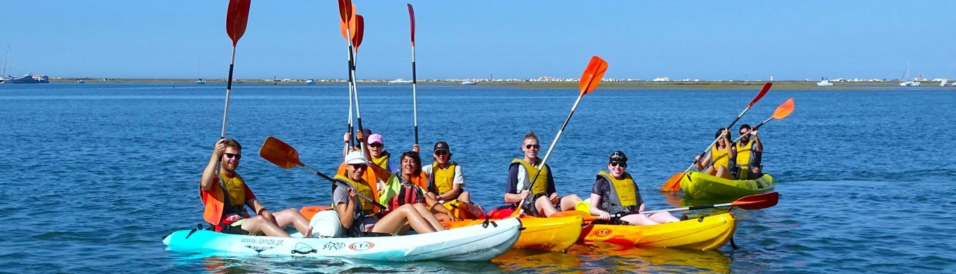 Un gruppo di partecipanti pagaiando lungo la Ria Formosa in una giornata di sole durante un tour in kayak da Faro con Lands Algarve.