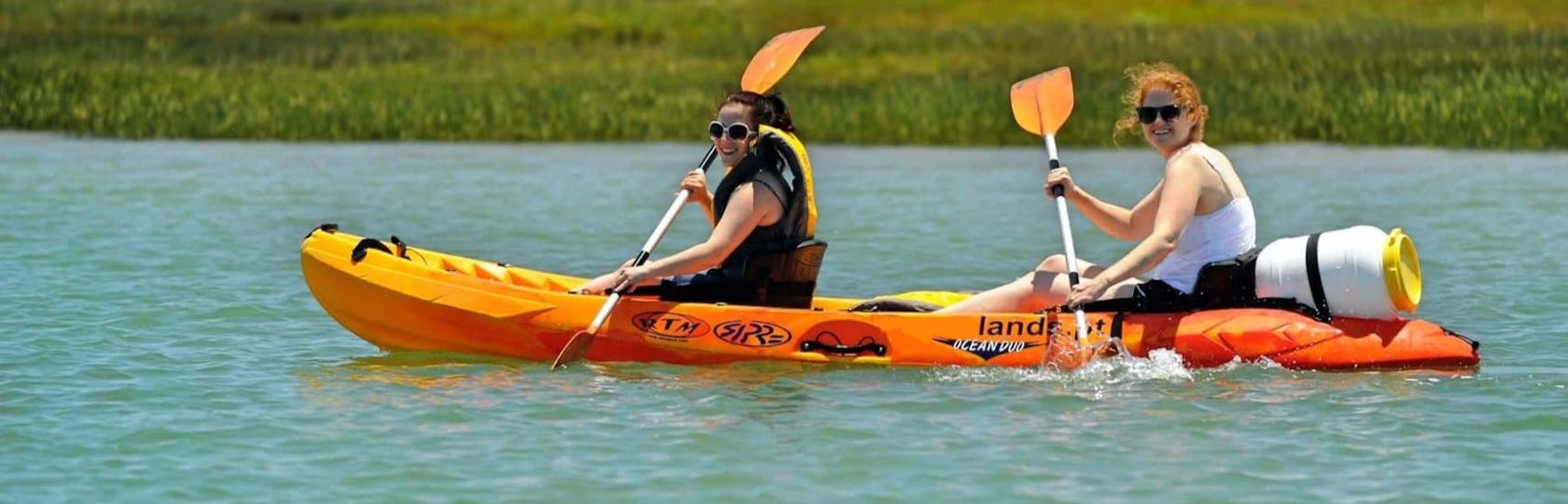 Two friends smiling paddling down the Ria Formosa having fun during a kayak rental from Faro with Lands Algarve.
