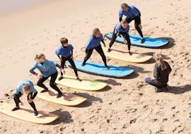 A group of people practicing on the beach during a surf lesson in Ericeira on Praia do Matadouro with Boardculture Surf Center.