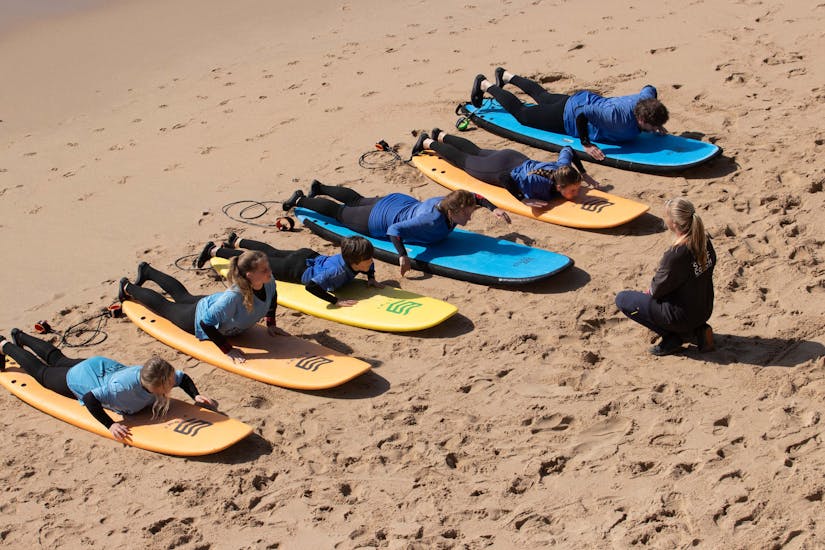A group of people learns how to paddle during a surf lesson in Ericeira on Praia do Matadouro with Boardculture Surf Center.