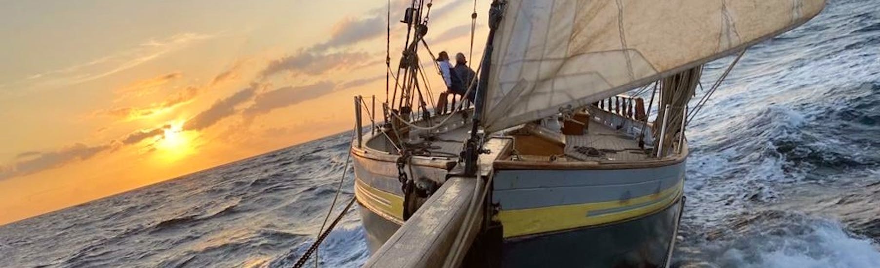 Leute machen eine Bootstour bei Sonnenuntergang auf einem Oldtimer-Segelboot zum Golf von Morbihan mit Lys Noir Morbihan.