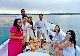 Foto di un gruppo di persone durante l'aperitivo su una barca di 18 Isola Bella durante il Giro in barca di Ortigia e delle grotte con aperitivo al tramonto.