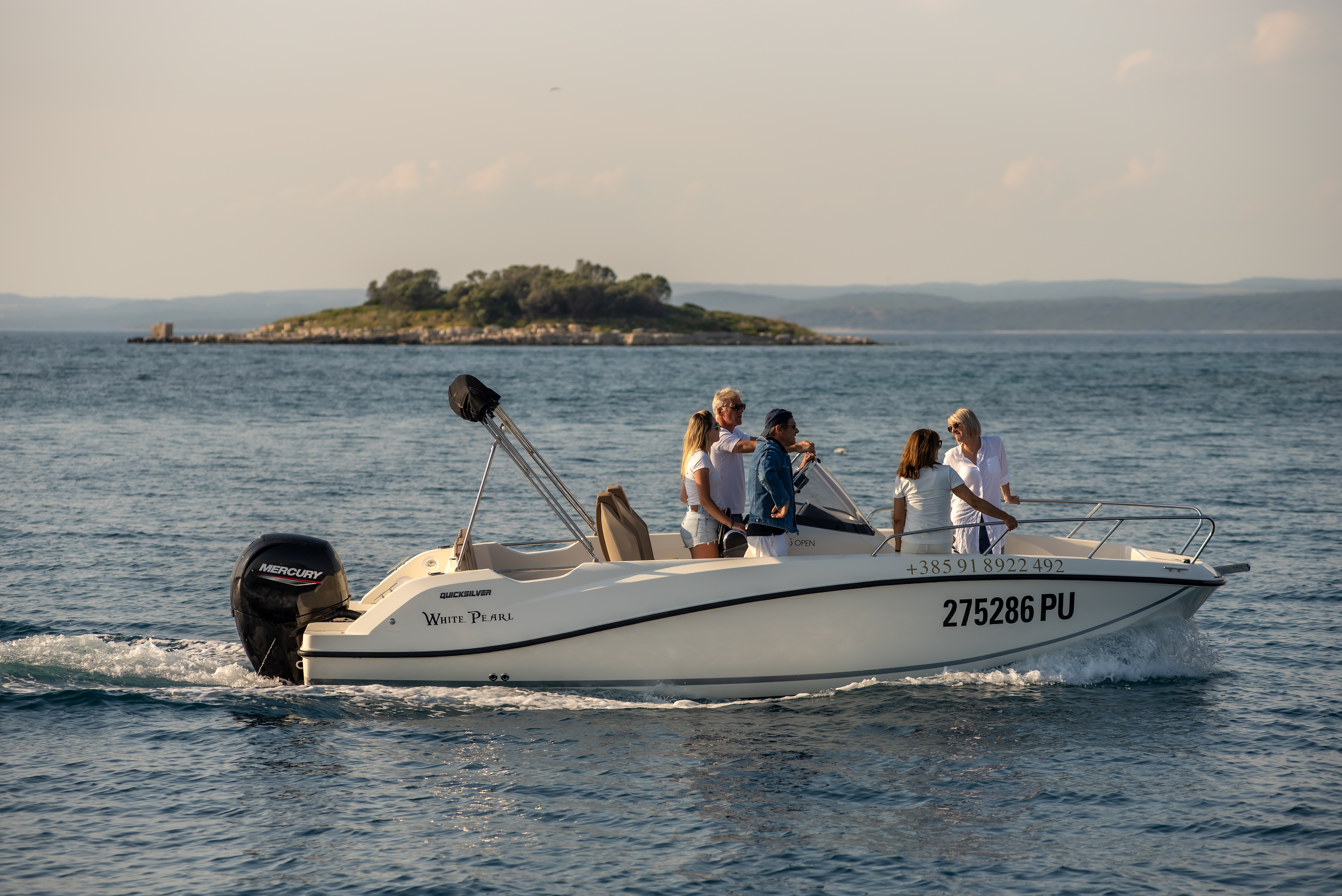 Un grupo de pasajeros disfruta navegando por el mar azul en una lancha motora blanca durante una excursión privada en barco a St. Jerolim o Veliki Brijuni con un crucero panorámico ofrecido por Sea Tours Istria Fažana.