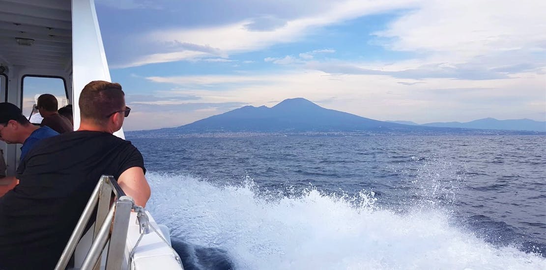 Ragazzo che guarda il Vesuvio dalla barca durante il Giro in barca a Capri da Napoli con sosta per nuotare con HP Travel Capri.
