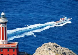 El barco de HP Travel navegando frente al faro de Anacapri durante la excursión de Nápoles a Capri con visita guiada a la Isla.
