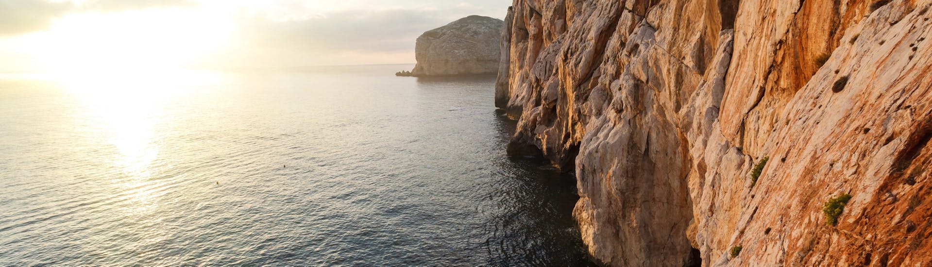 Photo of romantic sunset at the entrance to Neptune's Caves taken during a sailing trip from Alghero along the coast with sunset aperitif with Coral Sail Alghero.