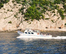 La barca di HP Travel che naviga davanti alla costa durante la Gita in barca da Sorrento a Capri con degustazione di limoncello.