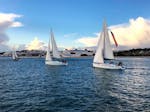Ein elegantes Segelboot setzt auf dem Tajo die Segel, und die Teilnehmer genießen den sonnigen Tag während einer morgendlichen Segeltour in Lissabon mit Taguscruises Lisboa.