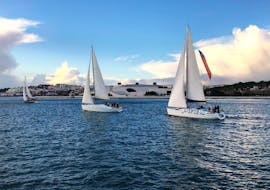 Ein elegantes Segelboot setzt auf dem Tajo die Segel, und die Teilnehmer genießen den sonnigen Tag während einer morgendlichen Segeltour in Lissabon mit Taguscruises Lisboa.