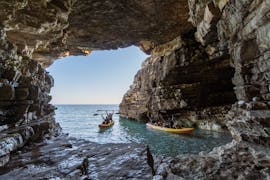 Mensen gaan een grot binnen tijdens de kajakexcursie naar de grot van Kaap Kamenjak met snorkelen met Kayaking Premantura.