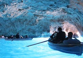 View of the inside of the Blue Grotto where people paddle in small boats during the Boat Trip around Capri with Blue Grotto with HP Travel.