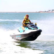 Ein Teilnehmer an einem sonnigen Tag beim Jetski fahren und Spaß haben im blauen Wasser des Guadiana Flusses bei einer Jetski-Safari entlang der Isla Canela mit JetSkiDream Huelva.