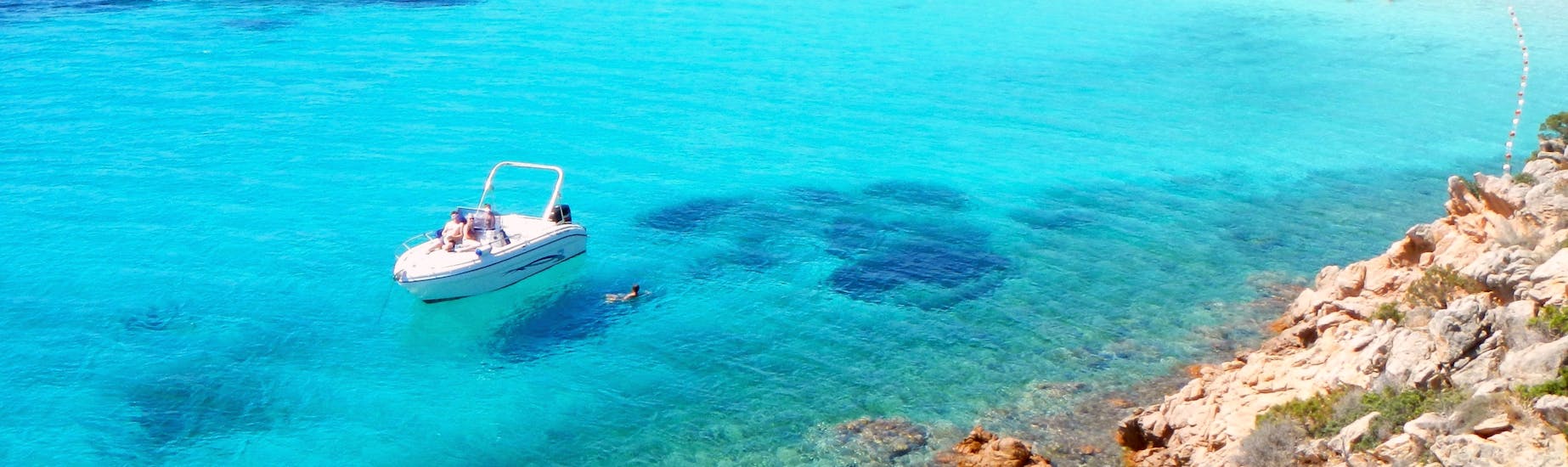 Our boat in the crystal clear water of a bay during the Private Boat Trip to the Tavolara Marine Park with Aperitif with Ecosport Sardinia.