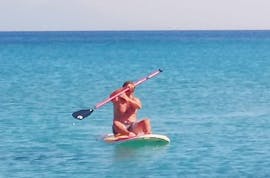 Un homme fait une Location de stand up paddle sur le plage de Kefalos avec Water Club Poseidon Kos.