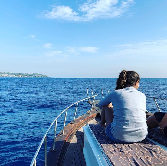 Girl sitting on the boat of Etna & Sea Excursions Catania looking at the sea during the Boat Trip in the Cyclops Islands Protected Area with Snorkeling.