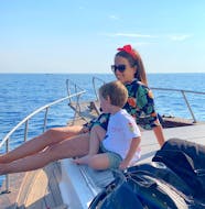 Une mère et son fils assis sur le bateau de Etna & Sea Excursions Catania pendant la balade en bateau dans la zone protégée des îles Cyclopes avec snorkeling.
