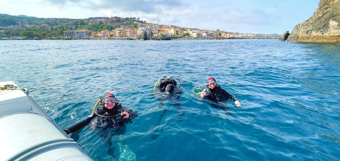 Persone con attrezzatura da sub in acqua durante il Battesimo del mare ad Aci Castello vicino Catania con Etna & Sea Excursions Catania.