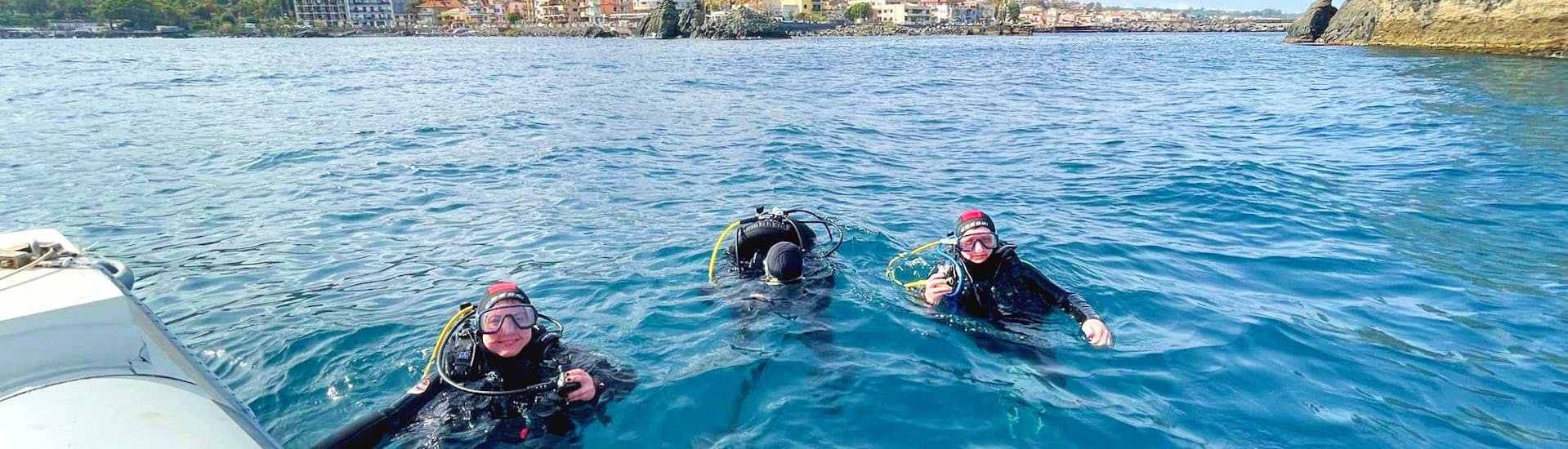 Mensen in de zee die duikuitrusting dragen tijdens de Trial Scuba Diving in Aci Castello bij Catania met Etna & Sea Excursions Catania.