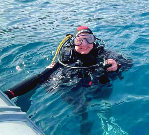 Una ragazza in acqua con attrezzatura da sub durante Battesimo del mare ad Aci Castello vicino Catania con Etna & Sea Excursions Catania.
