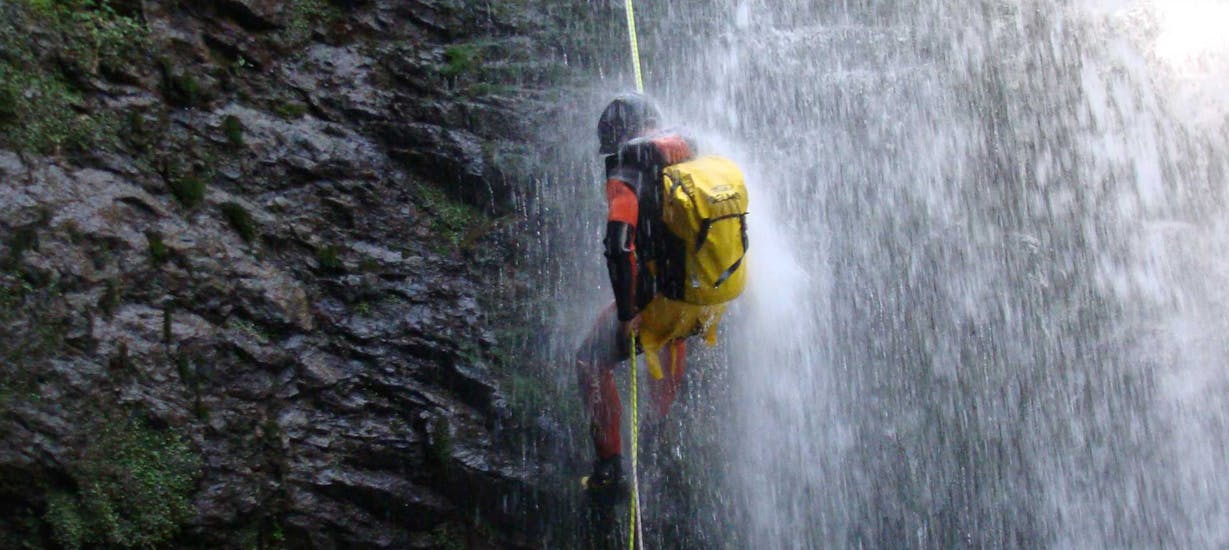 A guy in the waterfall while Canyoning in the Navedo River for Families with Cantabria Activa.