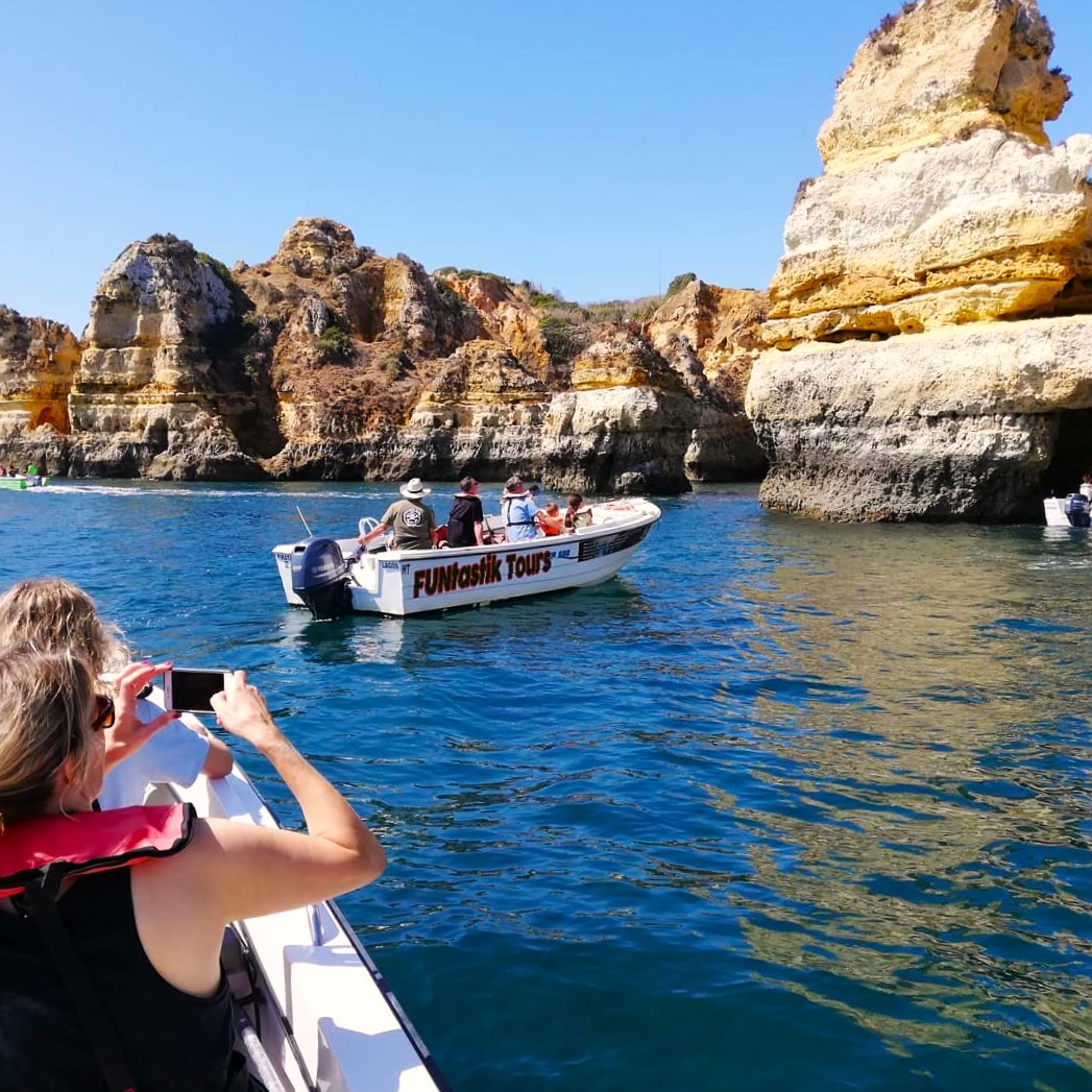 A group of participants admiring the impressive Benagil caves, as they approximate the entrance for a closer look during a boat trip from Lagos with Funtastik Tours Lagos.