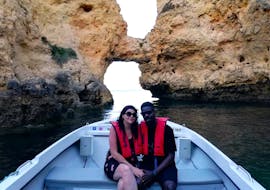 Un couple heureux pose amoureusement devant une grotte sur la côte de l'Algarve lors d'une Romantique balade privée en bateau au coucher du soleil depuis Lagos avec Funtastik Tours Lagos.