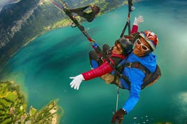 Una mujer y su piloto disfrutan del vuelo mientras vuelan en parapente en tándem, desde Beatenberg en Interlaken, con AlpinAir Paragliding Interlaken.