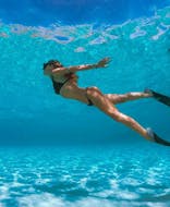 Une femme nageant pendant une balade en bateau semi-rigide à Cala Coticcio (Tahiti) avec snorkeling avec Scuba Revolution Cannigione.