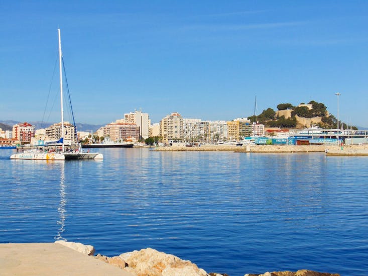 Der elegante und moderne Öko-Segelkatamaran segelt vor dem schönen Hafen von Málaga während eines ganztägigen Bootsausflugs ab Málaga entlang der Costa del Sol mit Mundo Marino Costa del Sol.