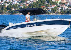 Mann fährt das Boot, das beim Bootsverleih in Seget Donji (bis zu 8 Personen) mit Space Fun Seget Vranjica ausgeliehen werden kann über die Gewässer in Kroatien.