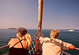 Dos personas haciendo un viaje en velero al atardecer desde Poreč con avistamiento de delfines con Santa Maria Boat Cruises Poreč.