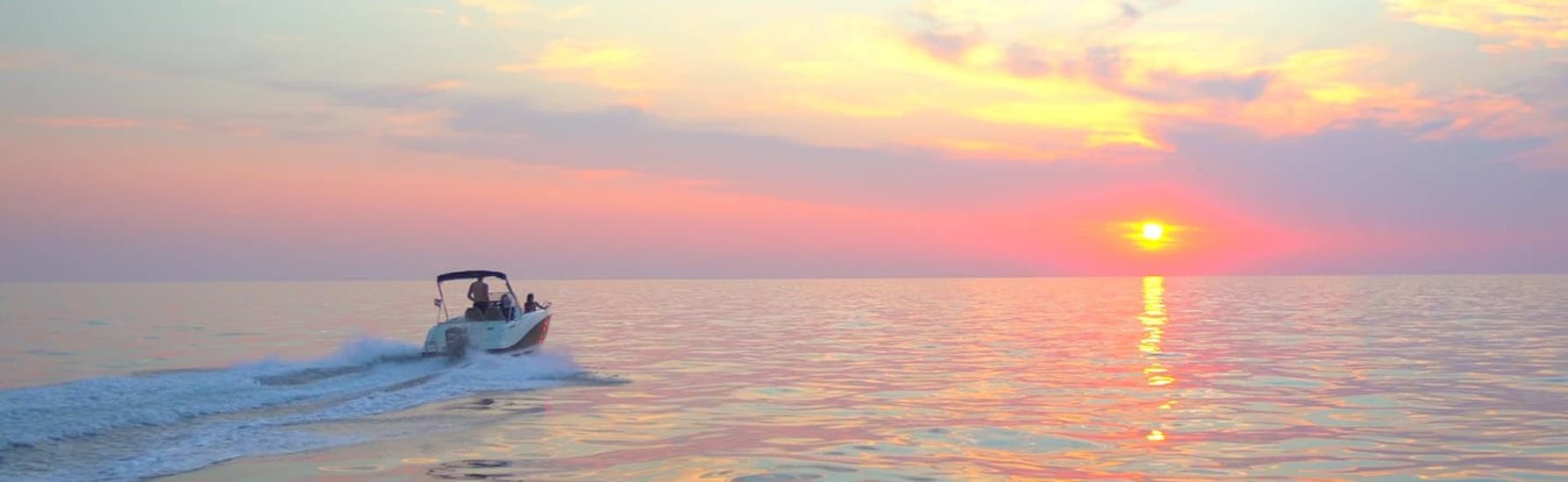 Un barco alquilado en Lux Rent A Boat & Jet Ski Vrsar navega hacia la puesta de sol.